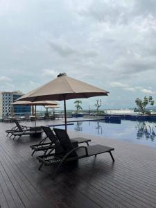 2 tumbonas y una sombrilla junto a la piscina en Wawa Guesthouse Pollux Habibie Batam Tower A 18, en Batam Centre