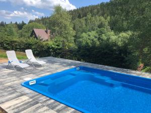 ein blauer Pool auf einer Terrasse mit zwei Stühlen in der Unterkunft Ski & Bike apartment Bublava in Bublava