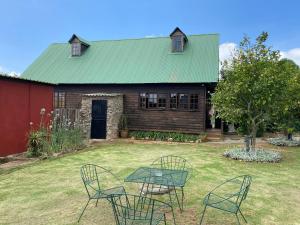 Bohemian Garden Cottages في Kaapsehoop: طاولة وكراسي أمام المنزل