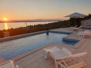 einen Pool mit Stühlen und Sonnenuntergang in der Unterkunft Villa Draga Crikvenica in Crikvenica