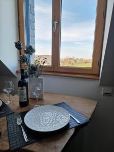 een tafel met een bord en een fles wijn en een raam bij L'Aurore de la Baie, vue sur le Mont-Saint-Michel in Huisnes-sur-Mer