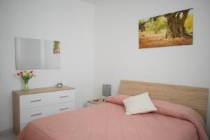 a bedroom with a pink bed and a dresser at La Casa del Carrubo in Cagliari
