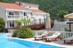 a hotel swimming pool with two chairs and an umbrella at Elegance Duplexes by Monte Aria in Herceg-Novi +31 photos