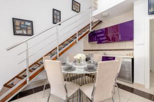 a dining room with a table and chairs and a staircase at Elegance Duplexes by Monte Aria in Herceg-Novi