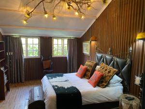 a bedroom with a bed with a black leather headboard at Bohemian Garden Cottages in Kaapsehoop