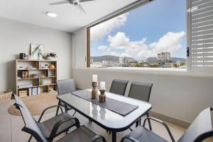 ケアンズにあるCity Escape at Loft Apartments - Cairns CBDのテーブルと椅子と大きな窓のあるダイニングルーム