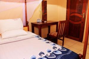 ein Schlafzimmer mit einem Bett, einem Tisch und einem Stuhl in der Unterkunft PrimeRose Hotel Mubende in Mubende