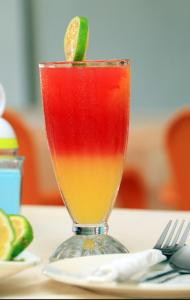 a drink in a glass with a lime on a table at PrimeRose Hotel Mubende in Mubende