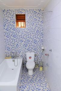 a bathroom with a toilet and a bath tub at PrimeRose Hotel Mubende in Mubende