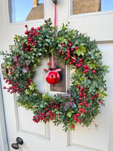 a christmas wreath on a door with a red ornament at Merriman Cottage in Chipping Campden