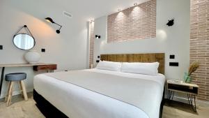 a bedroom with a white bed and a brick wall at Aparthotel Luz de Gades - Suites Spa Gym - Adults Only in Cádiz
