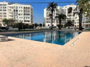 uma grande piscina com palmeiras e edifícios em Apartamento atardecer dorado em Valência