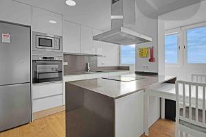 uma cozinha com armários brancos e electrodomésticos de aço inoxidável em Apartamento atardecer dorado em Valência