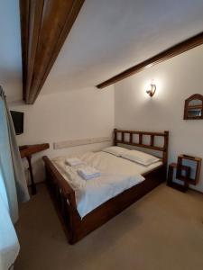 een slaapkamer met een houten bed met witte lakens bij Casa Zaharia Azuga in Azuga