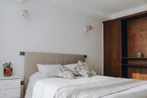 uma cama com lençóis brancos e almofadas num quarto em Departamento dúplex frente al mar en Reñaca em Viña del Mar
