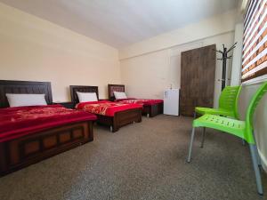 a bedroom with two beds and a green chair at Petraone in Wadi Musa