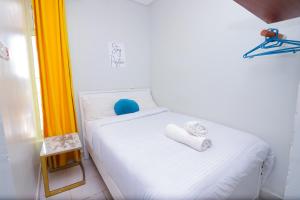 a white bed with two towels on it in a room at Cozy Studio along Ngong road-Nairobi in Nairobi