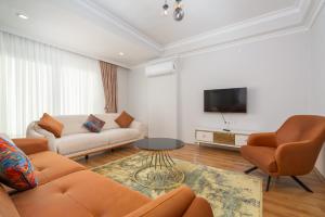 a living room with a couch and chairs and a tv at Family comfort in Antalya