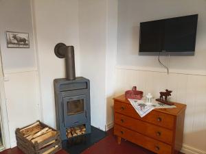 a room with a stove and a dresser with a television at Furulund in Gällö