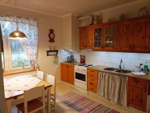 a kitchen with wooden cabinets and a table and a sink at Furulund in Gällö