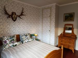 a bedroom with a bed and a dresser and a deer head on the wall at Furulund in Gällö