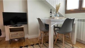 a dining room table with chairs and a television at CHECK-IN CASAS Casa Benas in Benasque