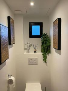 a bathroom with a toilet and some pictures on the wall at Au bal des hirondelles in Andé