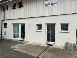a white building with three windows and a chair at Boardinghouse Rheinfelden 1 in Rheinfelden