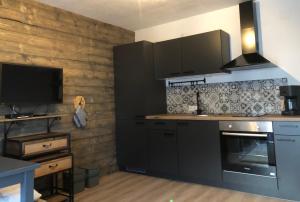 una cucina con armadi neri e una TV a parete di Appartement Zirbenduft Ferienhaus Fuenf Sinne a Döbriach