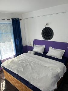 Schlafzimmer mit einem großen Bett mit einem lila Kopfteil in der Unterkunft Tiny Spot Hostel in Manali