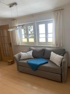 uma sala de estar com um sofá cinzento e janelas em Ferienwohnung Dani II em Gröbming