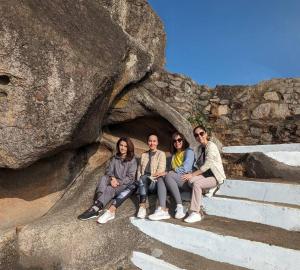 un grupo de personas sentadas en una formación rocosa en Valley Nest for 6-12 PAX, en Mount Abu