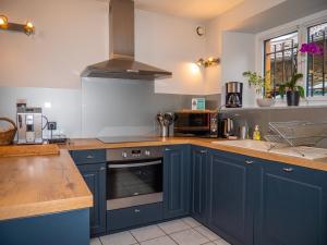 a kitchen with blue cabinets and a stove top oven at GITE DU TREUIL in Ignaux