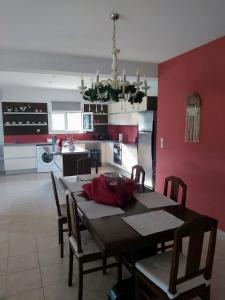 comedor con mesa y cocina con paredes rojas en Villa Marilena en Nafpaktos