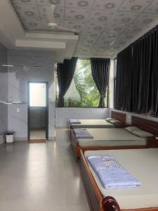 a bedroom with four beds and a large window at Nhà Nghỉ A&Em in Xã Bình Hòa