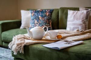 a green couch with a tea pot and cups on it at Alfred Apartment - Beautiful Central Bath Location in Bath