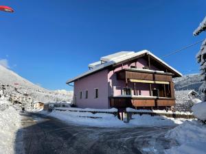 uma casa cor-de-rosa numa estrada coberta de neve em Haus Lila Stubaital em Fulpmes