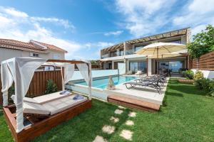 a backyard with a swimming pool and an umbrella at Sabbia D`oro Beach Villa in Méson Yerakaríon