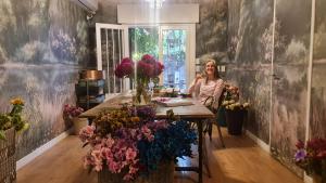 a woman sitting at a table with a bunch of flowers at mi casa de buenos aires in Buenos Aires