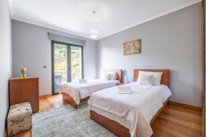 a bedroom with two beds and a large window at Yuri Big House in Ribeira Brava