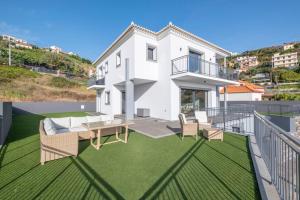 a white house with a balcony with a table and chairs at Yuri Big House in Ribeira Brava