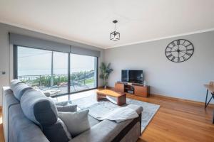 a living room with a couch and a large window at Yuri Big House in Ribeira Brava