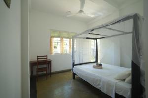 a bedroom with a canopy bed and a desk at Casa Tharin Madiha in Matara