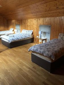 two beds in a room with wooden walls and wooden floors at The Loft, Ardfert in Ard Fhearta