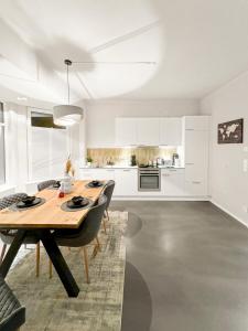 a white kitchen with a wooden table and chairs at Modern living: Hamburg & Baltic Sea within 30 min in Ahrensburg