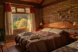 um quarto com uma cama grande e uma parede de tijolos em El Hostal del Rio em Aluminé