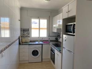 a white kitchen with a washing machine and a sink at Luxurious 2 bedroom apartment near Cabo Roig strip in Playas de Orihuela