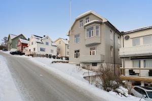 a snow covered street in a town with houses at Historical villa in the city center in Tromsø