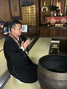 a man sitting on the floor next to a tire at 長徳寺宿坊　Temple Hotel in Shingu