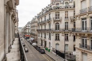 ulica miejska z samochodami zaparkowanymi przed budynkami w obiekcie Sweet Inn - Triangle d'Or w Paryżu